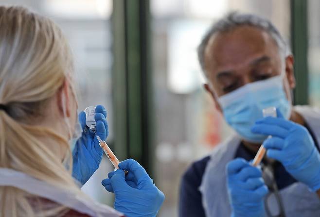 지난 2월5일 런던 동부 일포드에 있는 접종센터에서 의사 아닐 메타와 수습 간호사 엘리 불이 접종을 준비하며 아스트라제네카 백신을 주사기에 옮기고 있다. AP/연합뉴스