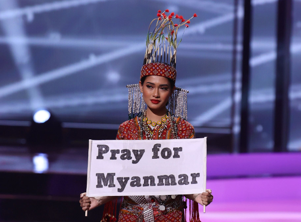 미국 플로리다에서 열린 미스 유니버스 대회에 미얀마 대표로 참석한 투자 윈 린이 지난 13일(현지시간) 전통의상 경연 도중 ‘미얀마를 위해 기도해달라’고 적힌 팻말을 들어 보이고 있다. AFP연합뉴스