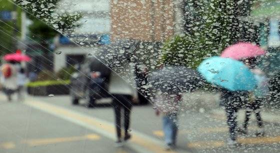 마른 빗방울로 얼룩진 차창 밖으로 시민들이 우산을 쓰고 있다.   연합뉴스