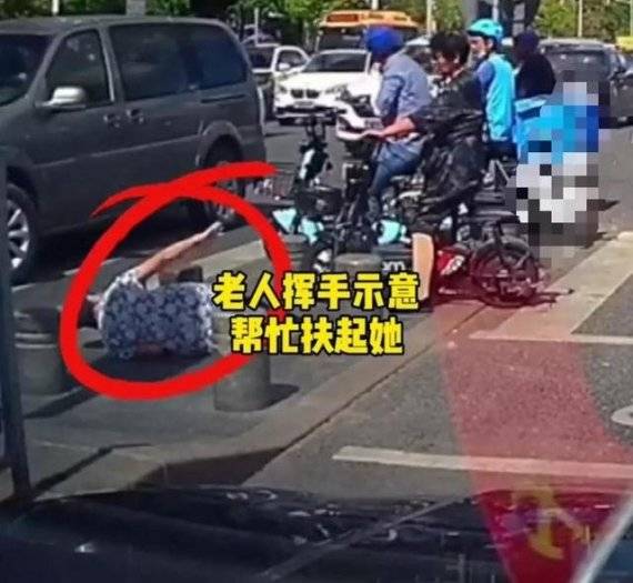중국 선전시의 한 횡단보도에서 길을 건너던 노인이 차량 진입 방지 구조물에 걸려 넘어진 뒤 오토바이 운전자들에게 손을 들어 보이고 있다. 중국 매체 펑파이 캡쳐.