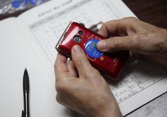 7일 한 어르신이 예방접종 확인 스티커를 휴대전화에 부착하고 있다. 우상조 기자