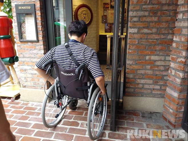 최민석 전문리서쳐가 휠체어를 타고 음식점 문 앞까지 가는 데에는 성공했지만, 문의 폭이 좁아 들어갈 수 없었다. 사진=노상우 기자