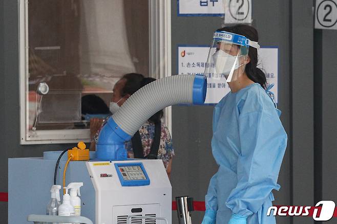 서울역 광장에 마련된 중구 임시선별진료소에서 의료진이 이동식 냉방기로 더위를 식히고 있다. /뉴스1