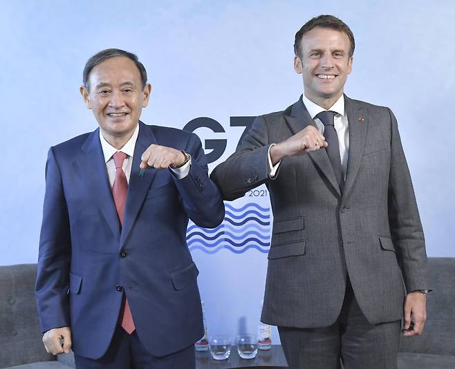 영국 콘월에서 열린 G7 정상회의에 참석 중인 스가 요시히데(菅義偉) 일본 총리(왼쪽)와 에마뉘엘 마크롱 프랑스 대통령이 12일 오후(현지 시각) 양자 회담에 앞서 팔꿈치 인사를 하는 모습. /연합뉴스