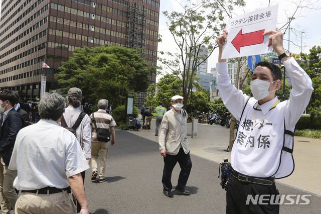 [도쿄=AP/뉴시스] 일본 수도 도쿄 시내에 설치된 코로나19 대량 접종센터앞에서 지난 5월24일 보건당국 직원이 시민들에게 길 안내를 하고 있다. 일본 정부는 이날 자위대 군의관과 간호장교를 동원해 도쿄도와 오사카에서 고령자를 대상으로 백신 투여를 시작했다. 2021.06.14.