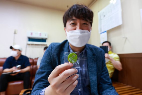 이준석 국민의힘 대표가 15일 오전 서울 노원구 한 병원에서 코로나19 백신(얀센) 접종후 배지를 들어보이고 있다. 사진=뉴시스