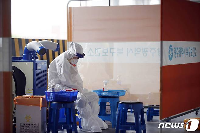 지난 11일 광주 북구선별진료소에서 신종 코로나바이러스 감염증(코로나19) 검사를 하는 보건소 의료진이 더위를 식히고 있다.(광주북구 제공)2021.6.11 /뉴스1 DB © News1