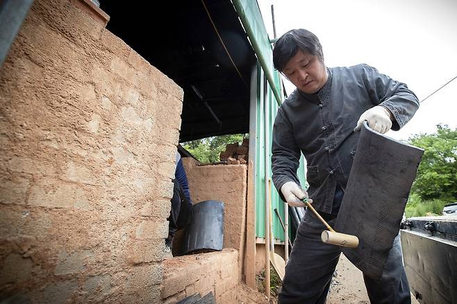 나무망치를 두드려 청음 검사를 하고 있다. 균열없이 잘 구워진 기와는 맑은 소리를 낸다.