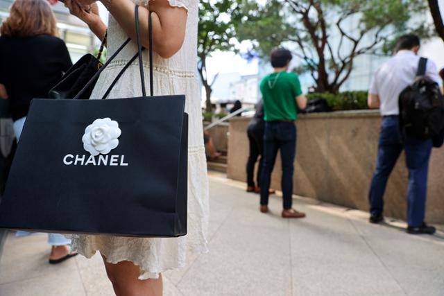 한 소비자가 샤넬 매장에서 구입한 물품이 담긴 쇼핑백을 들고 서 있다. 샤넬은 매장 입장 시 까다로운 조건을 제시하며 고객들을 맞고 있다. 연합뉴스
