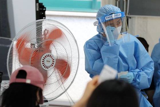 전국 대부분 지역에 폭염특보가 발효된 15일 서울 강남구 보건소에 마련된 강남구선별진료소에서 의료진이 선풍기로 더위를 식히며 흐르는 땀을 닦고 있다. 뉴스1