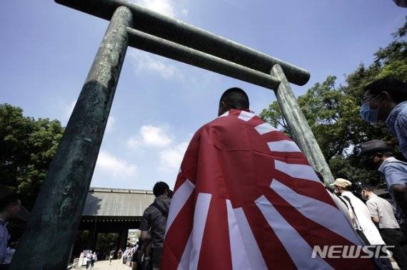 일본의 태평양전쟁 패전 75주년인 지난해 8월 15일 일본 도쿄 지요다구 야스쿠니신사에 한 남성이 일본 제국주의 침략전쟁의 상징인 욱일기를 몸에 두르고 참배 순서를 기다리고 있다. AP뉴시스