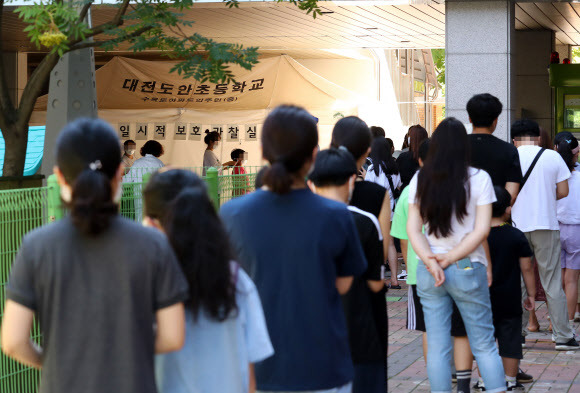 오전부터 길게 이어진 대기줄 - 22일 오전 대전시 서구 도안동 도안초등학교에 마련된 신종 코로나바이러스 감염증(코로나19) 임시 선별검사소에서 인근 지역 초등학생과 어린이집 원생 등이 검사받기 위해 대기하고 있다. 2021.7.22 연합뉴스