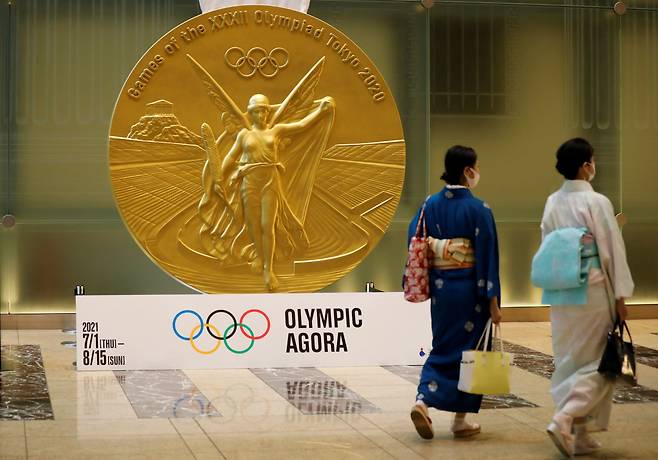 일본 수도 도쿄의 니혼바시 미쓰이 타워에 설치된 대형 올림픽 메달 모형 앞을 전통 복장을 한 여성들이 걸어가고 있다. /연합뉴스