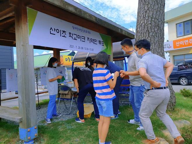 전남 해남 산이초교 학생들이 지난 22일 일본의 ‘욱일기’가 연상되는 학교 교표를 바꾸기 위해 주민들을 대상으로 투표를 진행하고 있다.  산이초교 제공
