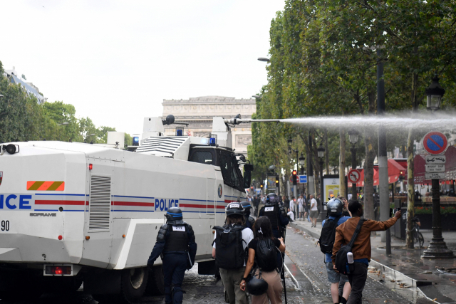 24일(현지시간) 프랑스 파리 샹젤리제 거리에서 경찰이 코로나19 백신 증명서에 반대하는 시위대를 향해 물대포를 쏘고 있다. /AFP연합뉴스