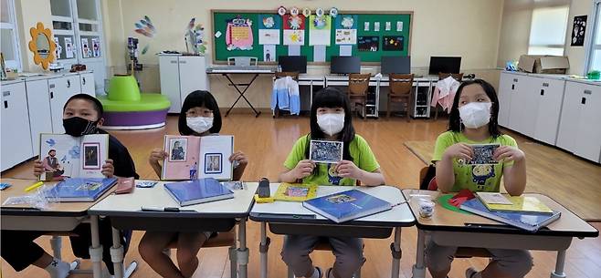 전남 신안군 흑산초등학교 홍도분교장 학생들이 책과 함께 선물받은 엽서를 노트에 붙여 작문수업을 하고 있다.