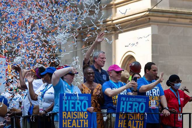 [뉴욕=신화/뉴시스] 빌 드 블라시오(가운데) 뉴욕 시장 7일(현지시간) 미국 뉴욕에서 시민들과 함께 색종이 테이프 행렬에 참여해 손을 흔들며 인사하고 있다. 이날 뉴욕시의 필수 근로자 수백 명이 코로나19로부터의 회복을 알리는 색종이 테이프 행렬에 참여했다. 이 행사는 코로나19 대유행 중에 일선에서 싸워야 했던 의료진, 응급구조대원, 교육 및 보육 종사자, 운송 근로자, 비상식량 공급 업체, 통신 및 배달 사업자 등 필수 근무자들을 기리기 위해 열렸다. 2021.07.08.