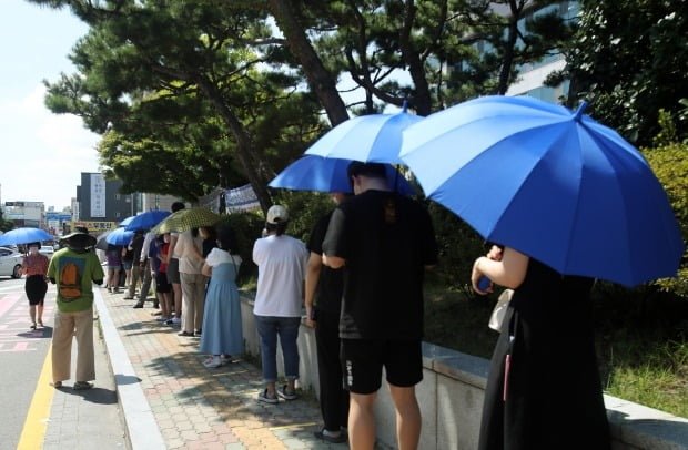 29일 광주 광산구 선별진료소에서 시민들이 구청에서 제공한 우산으로 햇볕을 가리고 줄 서 있다. /사진=연합뉴스
