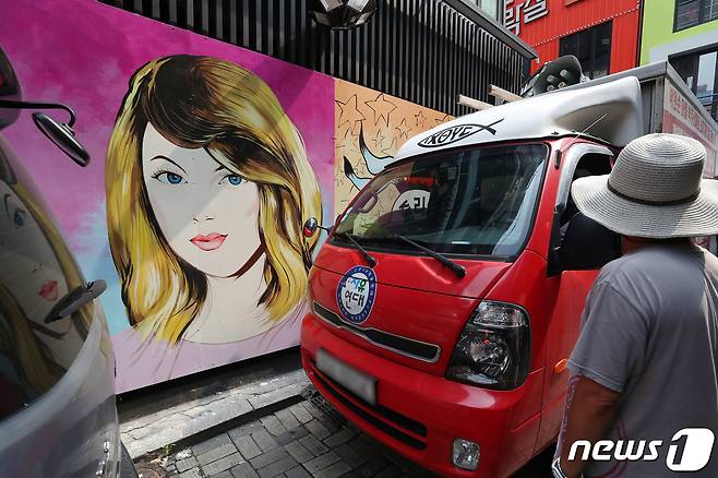 29일 서울 종로구의 한 서점 벽면에 그려진 윤석열 전 검찰총장의 배우자 김건희 씨를 비방하는 내용의 벽화를 보수단체 관계자들이 차량으로 막아서고 있다. 앞서 지난달 김건희씨는 자신이 '강남 유흥주점의 접객원 쥴리였다'는 루머에 대해 "누가 소설을 쓴 것＂이라고 해명했다. 윤석열 대선 예비후보 캠프는 지난 27일 김건희에 대한 루머가 확산되고 있는 것에 강력히 대응하겠다고 밝혔다. 2021.7.29/뉴스1 © News1 민경석 기자