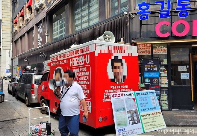 29일 서울 종로구 관철동의 한 중고서점 벽면에 설치된 '쥴리의 남자들' 이라는 벽화 앞을 보수 유튜버들이 동원한 차량이 가로막고 있다. / 사진 = 오진영 기자