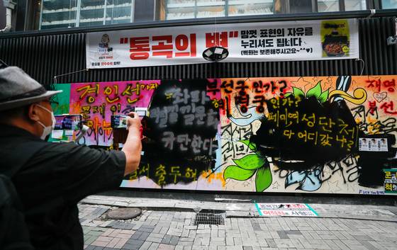 The same wall paintings by the end of the weekend, now covered in anti-government graffiti. [NEWS1]