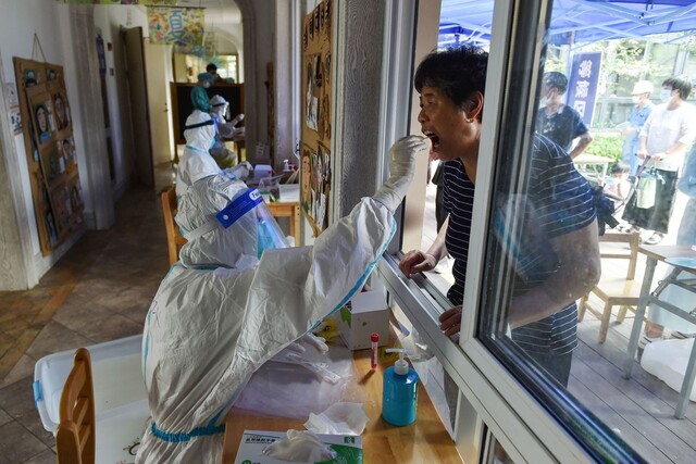 지난달 21일 이후 코로나19 확산세가 지속되고 있는 중국 장쑤성 난징에서 방역 요원이 핵산(PCR)검사를 위한 검체를 채취하고 있다. 난징/AFP 연합뉴스