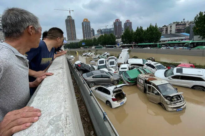 중국 허난성 정저우시 주민들이 지난달 20일 기록적인 폭우로 침수된 차량들을 바라보고 있다. 정저우/AFP연합뉴스