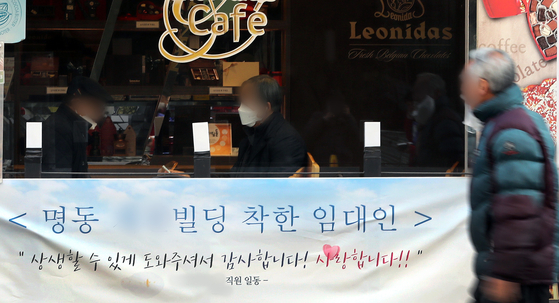 A passerby walks by a banner in Myeong-dong, central Seoul, thanking the landlord for lowering rents during the coronavirus pandemic on Feb. 24. [NEWS1]