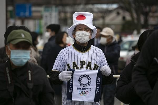 일본 후쿠시마에서 지난해 3월 24일 일본 국기 모자를 쓴 한 남성이 2020 도쿄올림픽 로고가 그려진 수건을 든 채 성화를 보기 위해 줄을 서고 있다./연합뉴스