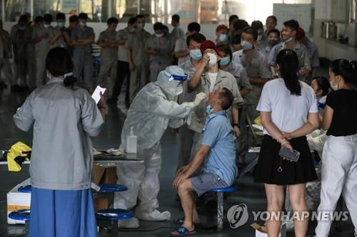 (우한 AFP=연합뉴스) 신종 코로나바이러스 감염증(코로나19) 기원지 논란을 빚는 중국 후베이성 우한의 한 자동차 부품 생산공장에서 지난 4일 직원들이 코로나19 핵산검사를 받고 있다. 15개월 만에 코로나19가 재발한 우한은 전날 16개 주택단지를 봉쇄하고 전 시민 1천200만 명을 대상으로 핵산검사를 시작했다.