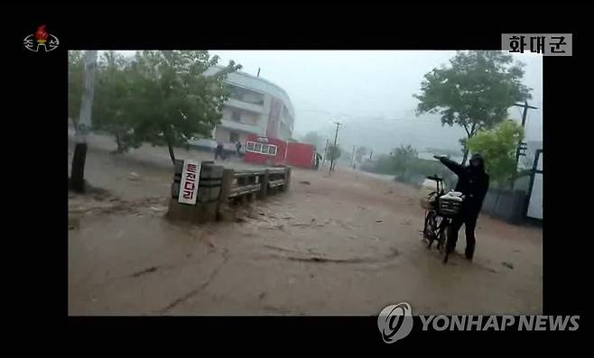 북한 함경북도 화대군에서 지난 11일 한 주민이 폭우로 침수된 도로로 자전거를 끌며 걷고 있다. [조선중앙TV 화면]
    [국내에서만 사용가능. 재배포 금지. For Use Only in the Republic of Korea. No Redistribution]