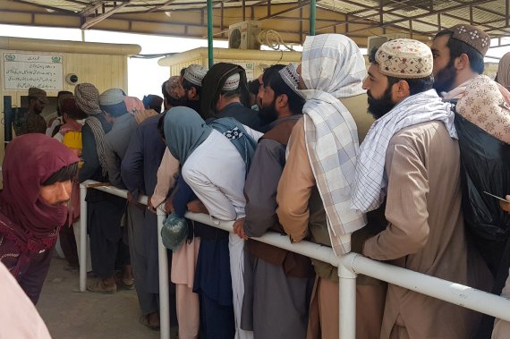 지난 15일(현지시간) 아프가니스탄에서 도착한 사람들이 파키스탄 국경에서 서류검사를 받기 위해 줄을 서서 기다리고 있다. 로이터뉴스1