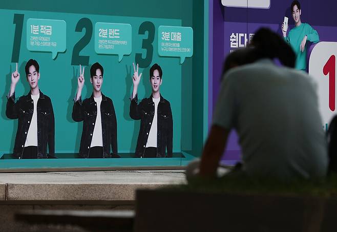 20일 서울 시내 한 은행에 내걸린 은행 금융상품 광고판 앞에 한 시민이 휴식을 취하고 있다. 연합뉴스