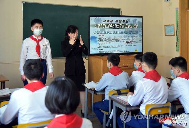 지난 5월 평양 락랑구역 충성초급중학교에서 코로나바이러스 감염증(코로나19) 방역을 위해 한 교사가 학생들에게 마스크 쓰는 법 등 방역 규정을 교육하고 있다. /평양 조선중앙통신=연합뉴스