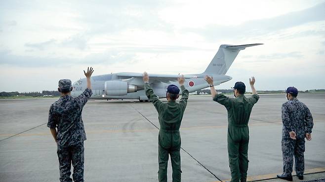 일본 항공자위대 C-2수송기가 지난 23일 아프간 내 일본인과 일본 협력 협력자 수송작전을 위해 이륙에 들어가자 관계자들이 손을 흔들어 환송하고 있다. 일본 항공자위대 이루마기지(사이타마현)=EPA연합뉴스