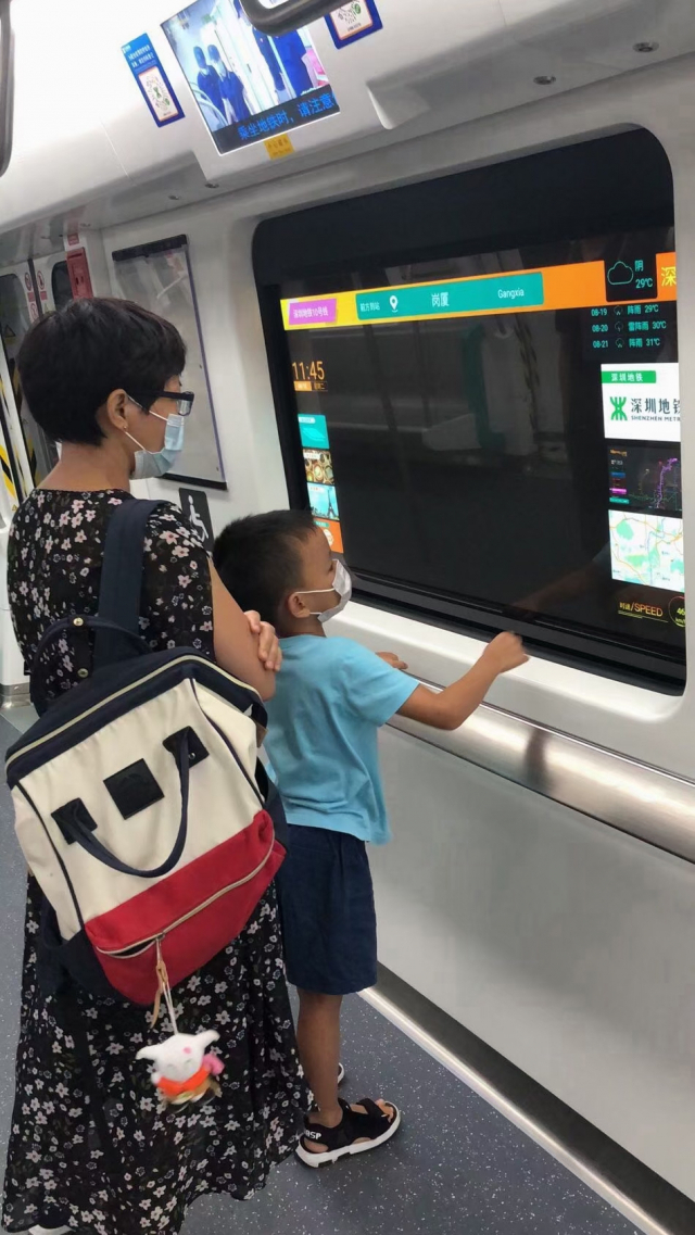 중국 심천 지하철 창문에 설치된 투명 OLED 패널을 승객이 바라보고 있다./사진제공=LG디스플레이
