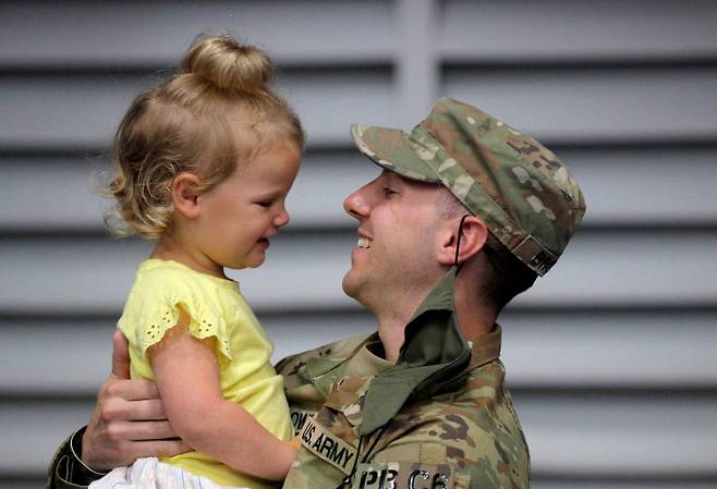 아프가니스탄에 파병됐다 돌아온 미군 장교가 6일(현지시간) 뉴욕주 포트 드럼에서 딸을 안고 재회의 기쁨을 나누고 있다. 포트 드럼|로이터연합뉴스