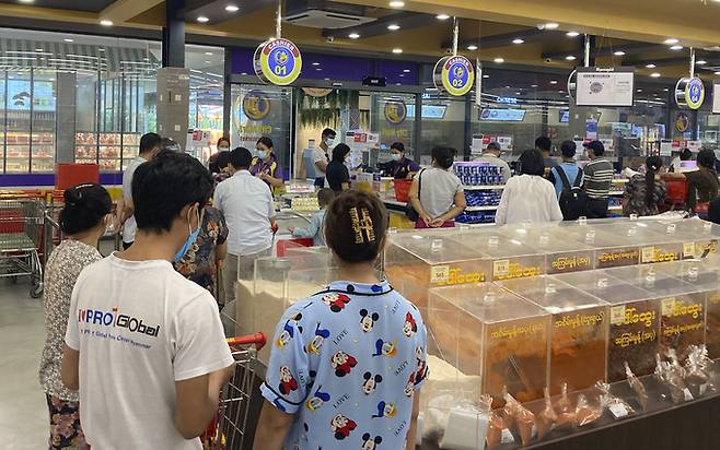 7일(현지시간) 미얀마 양곤의 한 슈퍼마켓에서 사람들이 생필품을 사기 위해 줄 지어 서 있다. 양곤=AP연합뉴스
