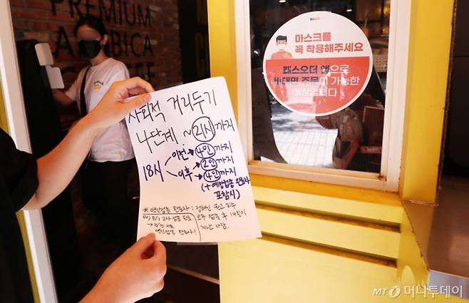 수도권 지역 사회적 거리두기 현행 4단계 조치가 추석 연휴를 포함해 4주간 연장 결정이 된 3일 서울 노원구의 한 카페에서 직원이 기존 거리두기 안내문을 떼고 있다.  재연장된 거리두기 조치는 식당과 카페 영업시간 기존  오후 9시에서 10시로 환원하고, 모임인원 제한은 낮시간 2인 이상, 저녁 6시 이후 4인 이상 접종완료자 포함의 경우 6명까지 사적 모임이 허용된다. /사진=김휘선 기자 hwijpg@
