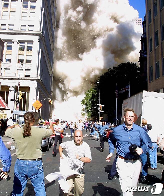 세계무역센터 건물 인근에 있던 사람들이 사고 현장을 등지고 긴박하게 도망치고 있다. 2001.09.11 © AFP=뉴스1