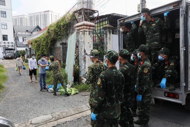 지난달 24일 베트남 호찌민 군 병력이 고위험 지역 주민들에게 비상 식료품을 전달하고 있다. 호찌민=로이터 연합뉴스