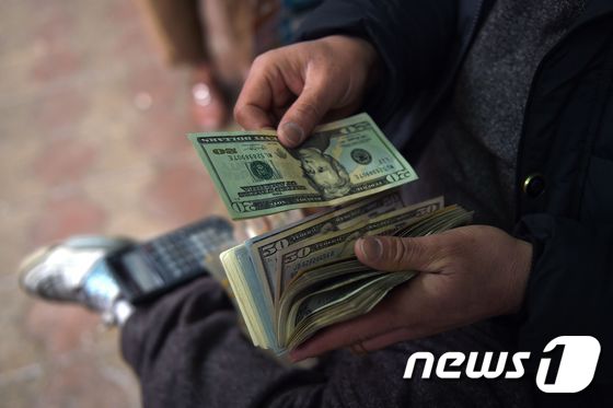 한 남성이 아프가니스탄 수도 카불 소재 사라이 샤카다 시장에서 환전한 미국 달러를 세고 있다. 2017.02.28