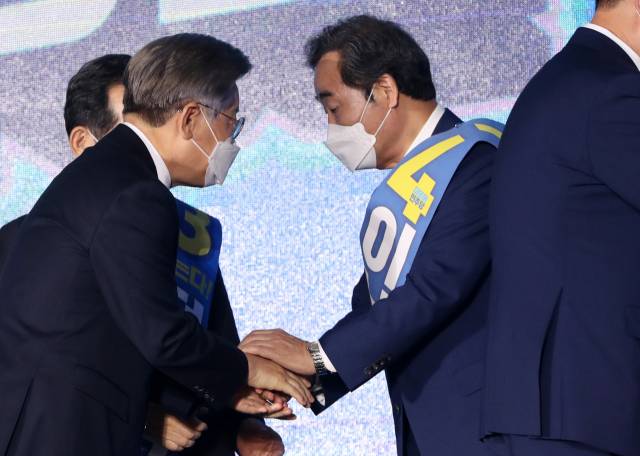 12일 오후 강원 원주시 오크밸리리조트 컨벤션센터에서 열린 더불어민주당 강원권역 순회경선 합동연설회에서 이낙연, 이재명 후보가 결과 발표를 들은 뒤 악수하고 있다./연합뉴스