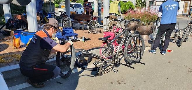 포항제철소 자전거수리봉사단이 11일 수해 지역에서 고장난 자전거 수리를 돕고 있다.
