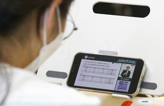 24일 서울 양천구 목동종로학원에서 학생들이 휴대폰으로 비대면으로 열린 2022수시 최종지원전략 설명회를 보고있다./사진=뉴시스