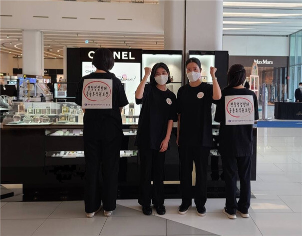 한 백화점 샤넬 화장품 매장 직원이 지난 14일 ‘연장영업 반대·공동휴식권 보장’이라는 문구가 적힌 등자보를 착용한 모습. 백화점면세점판매서비스노조 제공