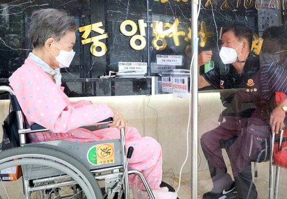 지난 13일 오전 부산 중구 중앙나라요양병원에서 신석곤(86)씨가 아내 김귀령(84)씨와 비접촉 면회를 하고 있다. 연합뉴스