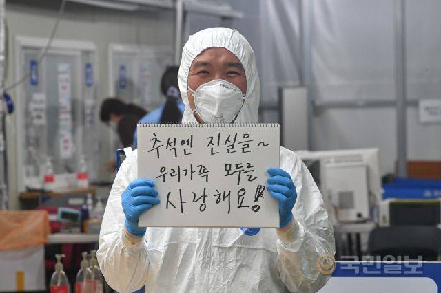 김동국 송파구청 주무관이 지난 7일 서울 송파구보건소 선별진료소 앞에서 가족들에게 보내는 메시지를 들고 있다.