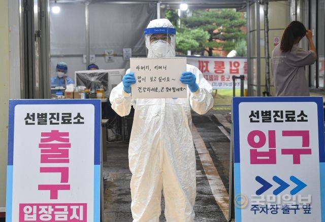 강영욱 송파구청 주무관이 지난 7일 서울 송파구보건소 선별진료소 앞에서 부모님께 보내는 메시지를 들고 있다.