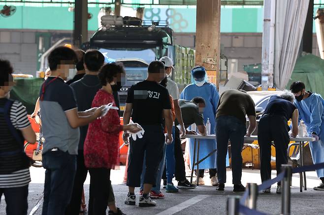 지난 12일 오전 서울 송파구 가락농수산물종합시장 내에 설치된 찾아가는 임시선별진료소에서 시장 종사자 및 방문자들이 선별검사를 받기 위해 줄을 서있다. / 연합뉴스